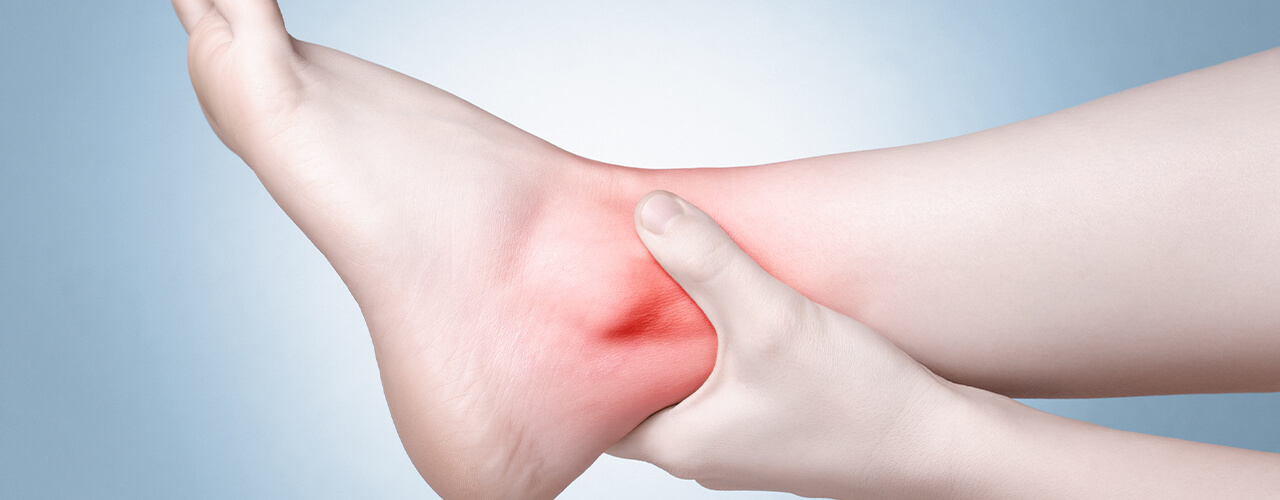 Person holding their heel and ankle in pain